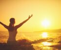 woman on beach at sunset with arms outstretched