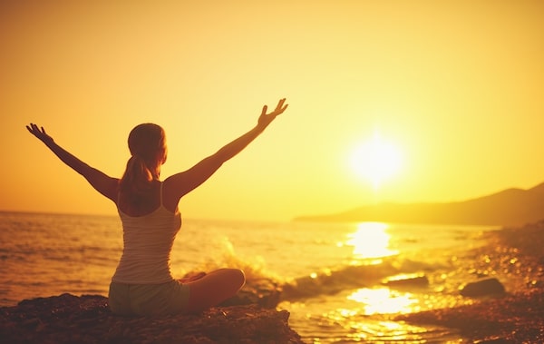 woman on beach at sunset with arms outstretched