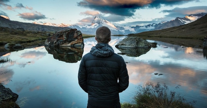 man standing looking out at lake