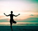 Silhouette of person in yoga tree pose on the beach