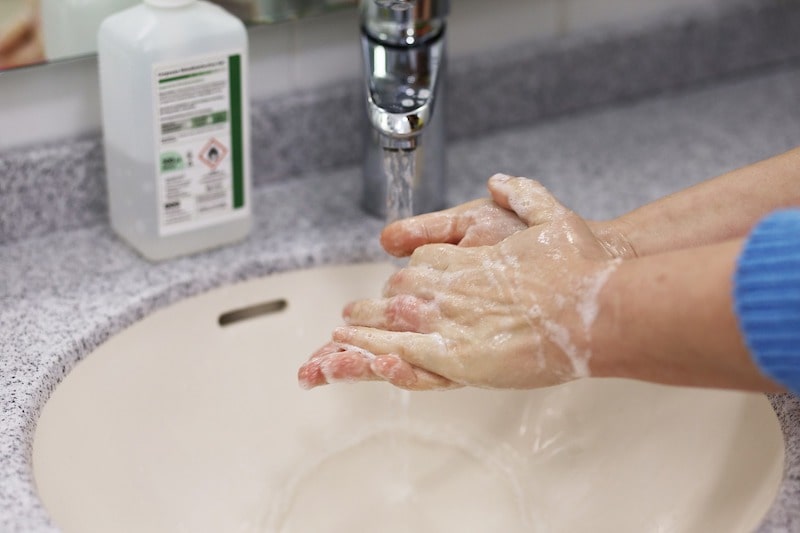 close up of person washing hands in small sink