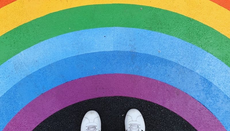 person standing on floor painted with rainbow stripes