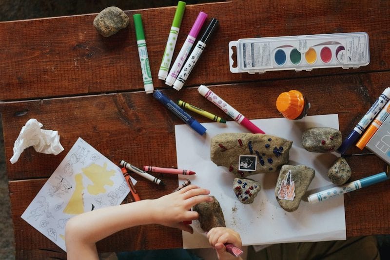 child coloring on rocks