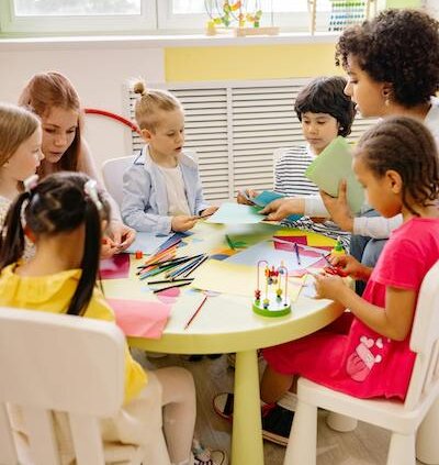 children in classroom sitting around table with teacher