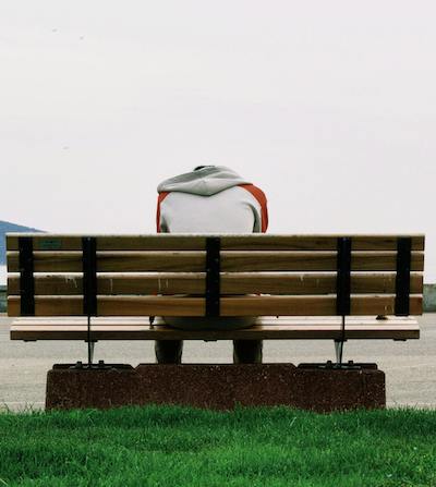man alone on bench with head lowered